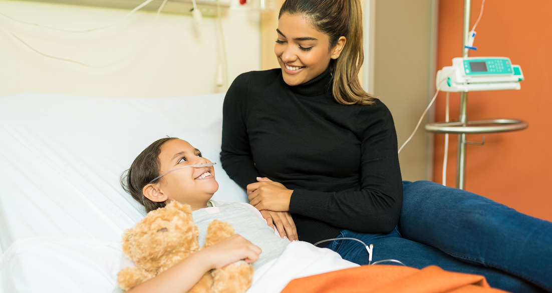 smiling-woman-talking-sick-daughter-while-sitting-bed-hospital 1 smiling-woman-talking-sick-daughter-while-sitting-bed-hospital